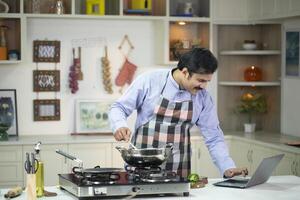 Husband Cooking While Watching On Laptop photo