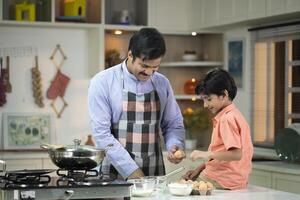 Son With Father Cracking Eggs To Make An Omelette photo