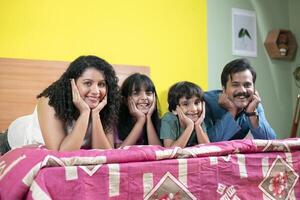 Cheerful Family Lying On Bed While Posing In Front Of Camera photo