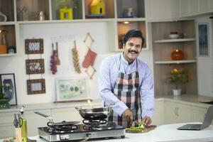 Elegant Man In Apron Smiling While Looking At Camera photo