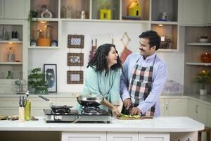 Joyful Lady Looking At Husband While Cooking In Kitchen photo