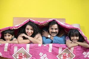 Happy Asian Family In Bed Playing Under Blanket photo
