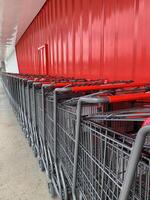 Shopping carts are arranged neatly against the red wall background photo