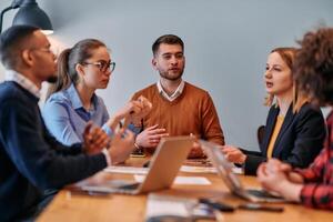 In the vibrant ambiance of a modern startup office, a diverse team of business professionals engage in discussions on various projects and develop new business strategies, epitomizing creativity and photo