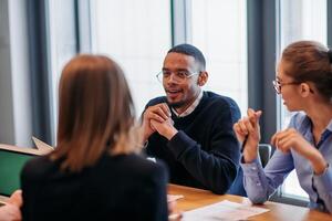 In the vibrant ambiance of a modern startup office, a diverse team of business professionals engage in discussions on various projects and develop new business strategies, epitomizing creativity and photo