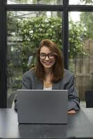 Young woman in eyeglasses working with laptop while sitting at cafe photo