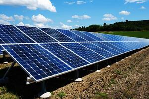 un fila de solar paneles sentado en parte superior de un lozano verde campo siguiente a un montaña foto
