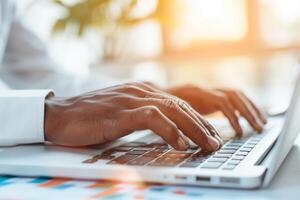 Close-up of hands typing on a laptop keyboard in a bright office setting with sunlight through the window, representing productivity and technology. photo