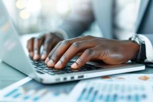 Close-up of hands typing on a laptop keyboard with charts on the desk, representing business analysis and productivity in a modern workplace. photo