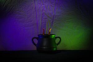 Black Cauldron With Witch Legs Under Colorful Neon Lighting photo