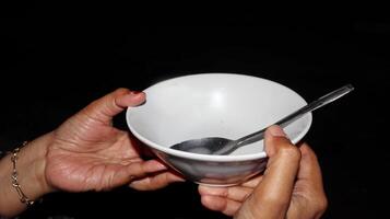 Hand holding empty white bowl with spoon photo
