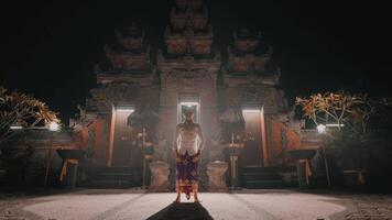 Person in traditional attire in front of illuminated temple at night video