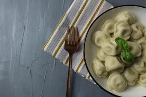 Serving food with basil leaf with fork napkin dumplings in bowl bowl top view with space for copyspace recipe text photo
