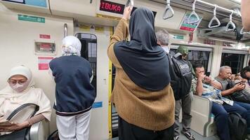 Jakarta, Indonesia on January 9 2024. The atmosphere in one of the Jakarta LRT carriages which is not too busy, looks like passengers can still sit and there are some standing. Men and women, everyone video