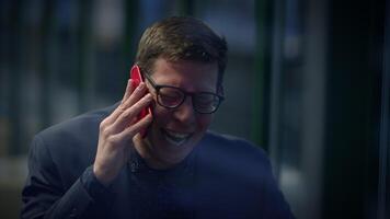 A happy businessman is smiling during a phone conversation in an indoor office setting video