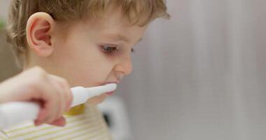 Close-up of a young boy brushing teeth with electric toothbrush video