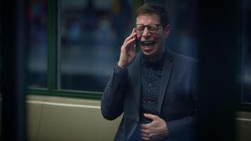 A businessman in a suit is laughing on the phone in a modern office, showing positivity video