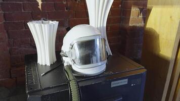 A vintage astronaut helmet displayed alongside unique sculptures, representing a significant piece of space exploration history. Perfect for themes related to space and technology. video