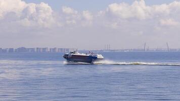 A high-speed boat cruises across the calm blue sea under a clear sky with fluffy clouds, creating a serene and dynamic maritime scene with a distant city skyline video