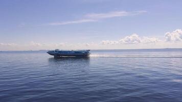 A high-speed boat cruises across the calm blue sea under a clear sky with fluffy clouds, creating a serene and dynamic maritime scene with a distant city skyline video