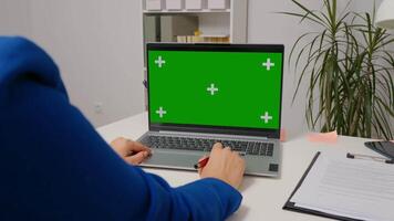 Woman watching webinar on laptop computer with mock up green screen chroma key display. video