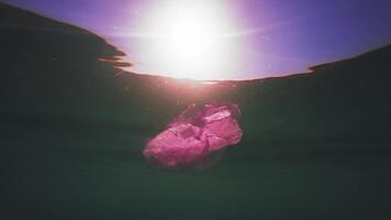 Plastic trash slowly drifts under the surface of blue water in the sunlight. The problem of ocean pollution with plastic waste. Plastic trash floats underfoot video