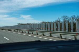 A road with a long line of metal posts with red hearts on them. The road is empty and the sky is clear. photo