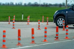 A row of orange and white traffic cones are lined up on a road. The scene is quiet and peaceful, with no cars or people in the area. photo