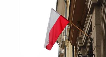 The Polish national flag flies on the facade of a building in the historic city, symbolizing patriotism. white background, banner with copy space photo