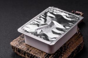 Rectangular plastic box with yogurt or cheese hermetically sealed with a foil lid photo
