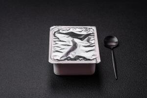 Rectangular plastic box with yogurt or cheese hermetically sealed with a foil lid photo