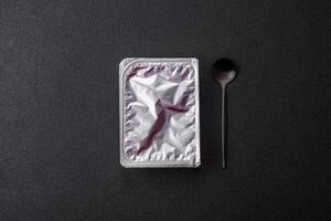 Rectangular plastic box with yogurt or cheese hermetically sealed with a foil lid photo