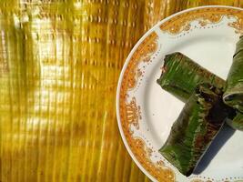 Indonesian tradisional food called lemper made from steamed glutinous rice with chicken meat wrapped with banana leaf photo