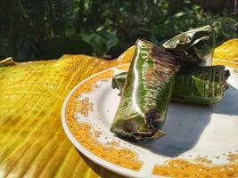 Indonesian tradisional food called lemper made from steamed glutinous rice with chicken meat wrapped with banana leaf photo
