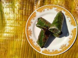 Indonesian tradisional food called lemper made from steamed glutinous rice with chicken meat wrapped with banana leaf photo