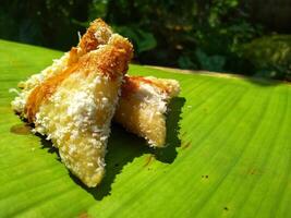 lupis cake is a traditional snack from Indonesia that has a soft and chewy texture made from glutinous rice that has a triangular shape served with grated coconut topping and sweet sauce, street food photo