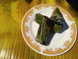 Indonesian tradisional food called lemper made from steamed glutinous rice with chicken meat wrapped with banana leaf photo