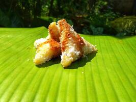 lupis cake is a traditional snack from Indonesia that has a soft and chewy texture made from glutinous rice that has a triangular shape served with grated coconut topping and sweet sauce, street food photo