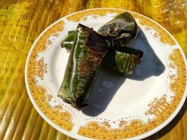 Indonesian tradisional food called lemper made from steamed glutinous rice with chicken meat wrapped with banana leaf photo