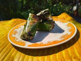 Indonesian tradisional food called lemper made from steamed glutinous rice with chicken meat wrapped with banana leaf photo
