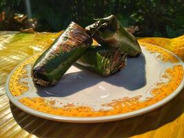 Indonesian tradisional food called lemper made from steamed glutinous rice with chicken meat wrapped with banana leaf photo