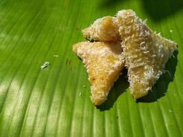 lupis cake is a traditional snack from Indonesia that has a soft and chewy texture made from glutinous rice that has a triangular shape served with grated coconut topping and sweet sauce, street food photo