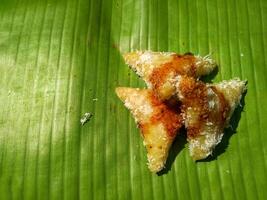 lupis cake is a traditional snack from Indonesia that has a soft and chewy texture made from glutinous rice that has a triangular shape served with grated coconut topping and sweet sauce, street food photo