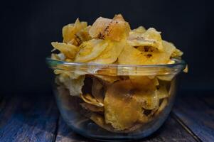 Keripik pisang or Banana crackers is a traditonal Indonesian snack. Made from banana and sugar. Sweet and crispy. with wooden background photo