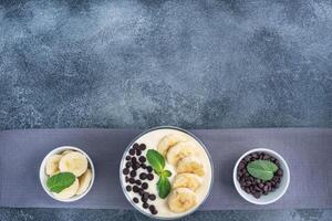 Healthy breakfast, dessert with milk yogurt banana and chocolate on a plate. Dark concrete background. Top view, copy space. photo