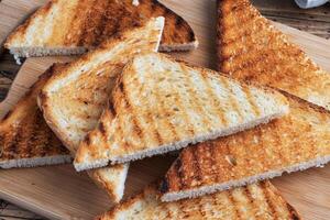 Slices of crispy bread toast for sandwiches on a cutting board, wooden rustic background. Close up. photo