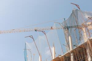 New building construction process. Safety nets, structural beams highlight ongoing work. Multi-level architecture. Ideal for articles on urban development, real estate investment. Copy space for text. photo