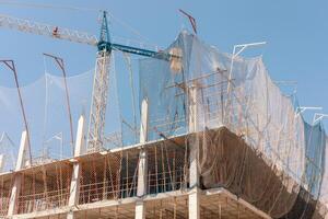 New building construction process. Safety nets and structural beams highlight ongoing work. Detailed shot of multi-level architecture. Ideal for articles on urban development, real estate investment. photo