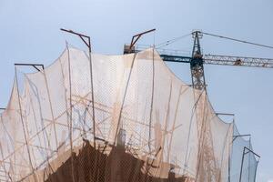 New building construction process. Safety nets and structural beams highlight ongoing work. Detailed shot of multi-level architecture. Ideal for articles on urban development, real estate investment. photo