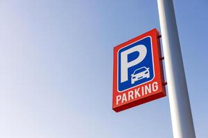Red and blue parking sign against clear sky, copy space for text. Perfect for use in content related to urban planning, transportation, city infrastructure, public parking facilities. Carpark price. photo